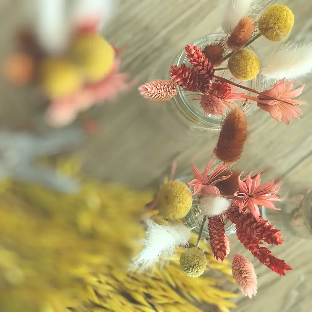 fleurs séchées colorées jaune et roses dans un petit vase en verre pour la préparation d'un atelier