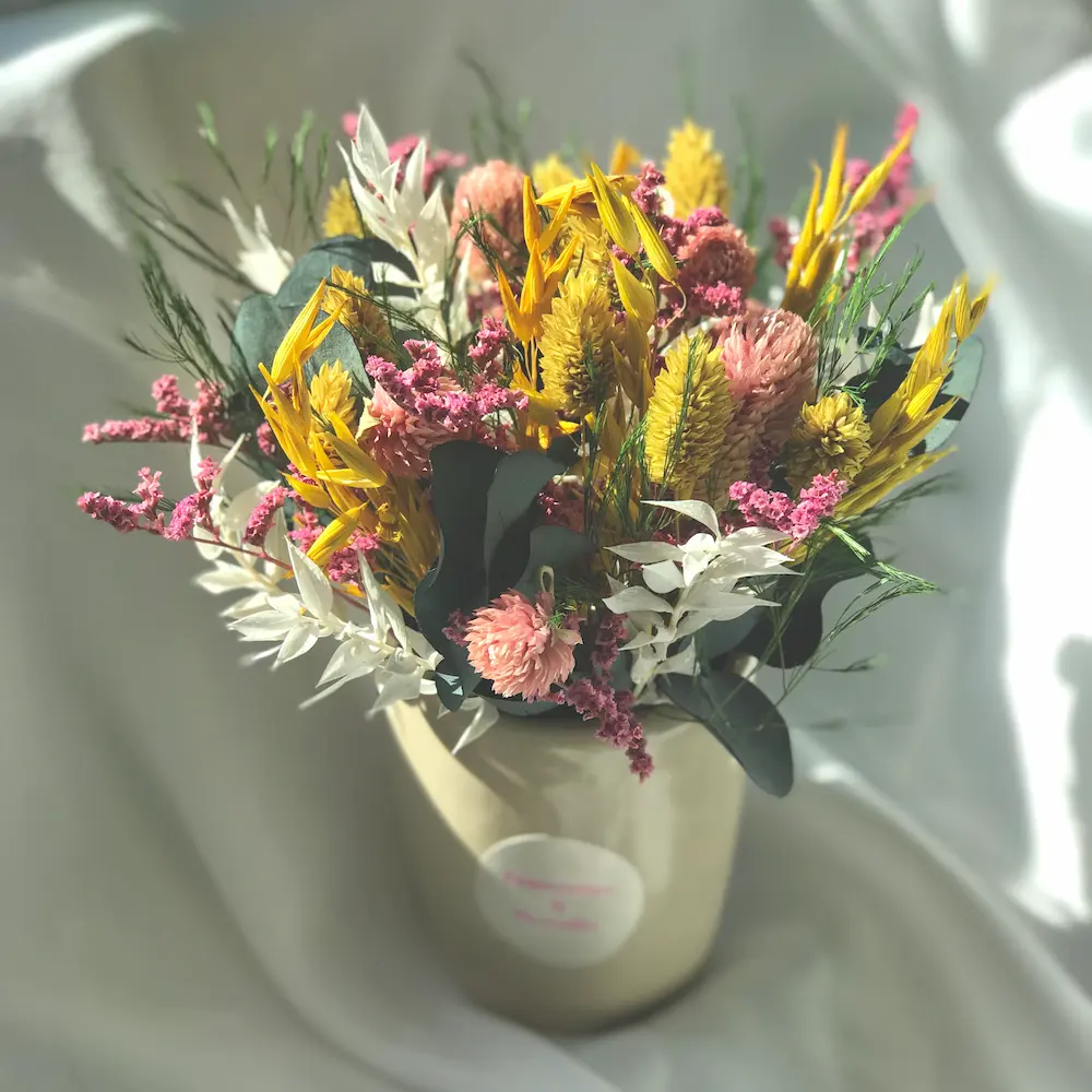 composition champêtre couleurs jaune et rose,avec des fleurs séchées et stabilisées dans un pot en céramique beige